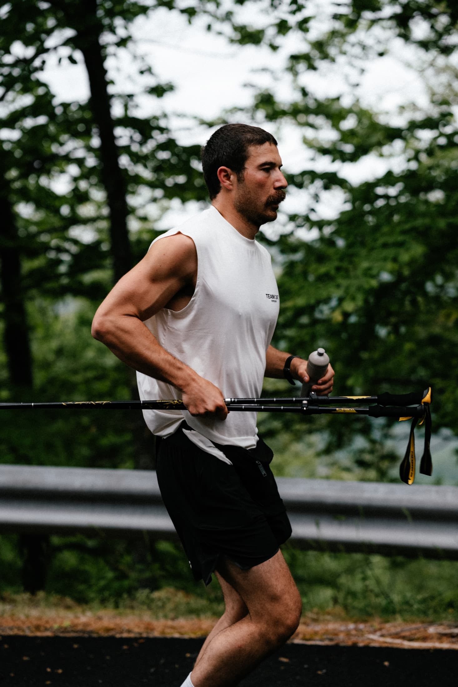 Lucas Nicolaou running to the right with poles and a water bottle